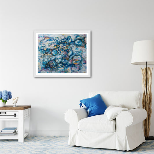 Vathi – atmospheric abstract painting with layered blue, white, and subtle gold textures, framed in light wood, styled above a white armchair with blue cushions in a coastal-inspired living room.